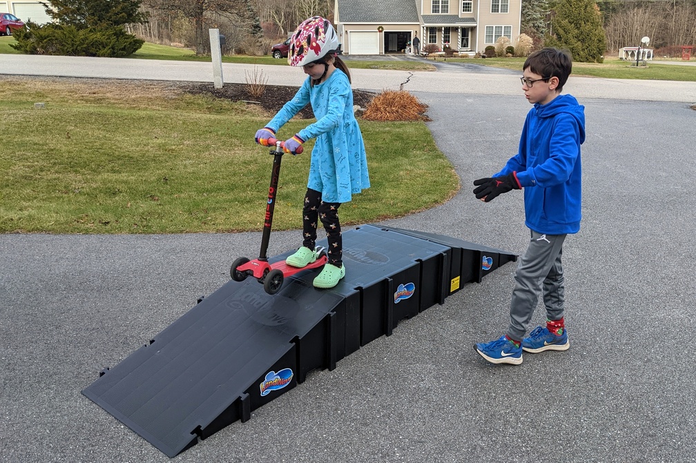 Teaching His Sister a Scooter Trick